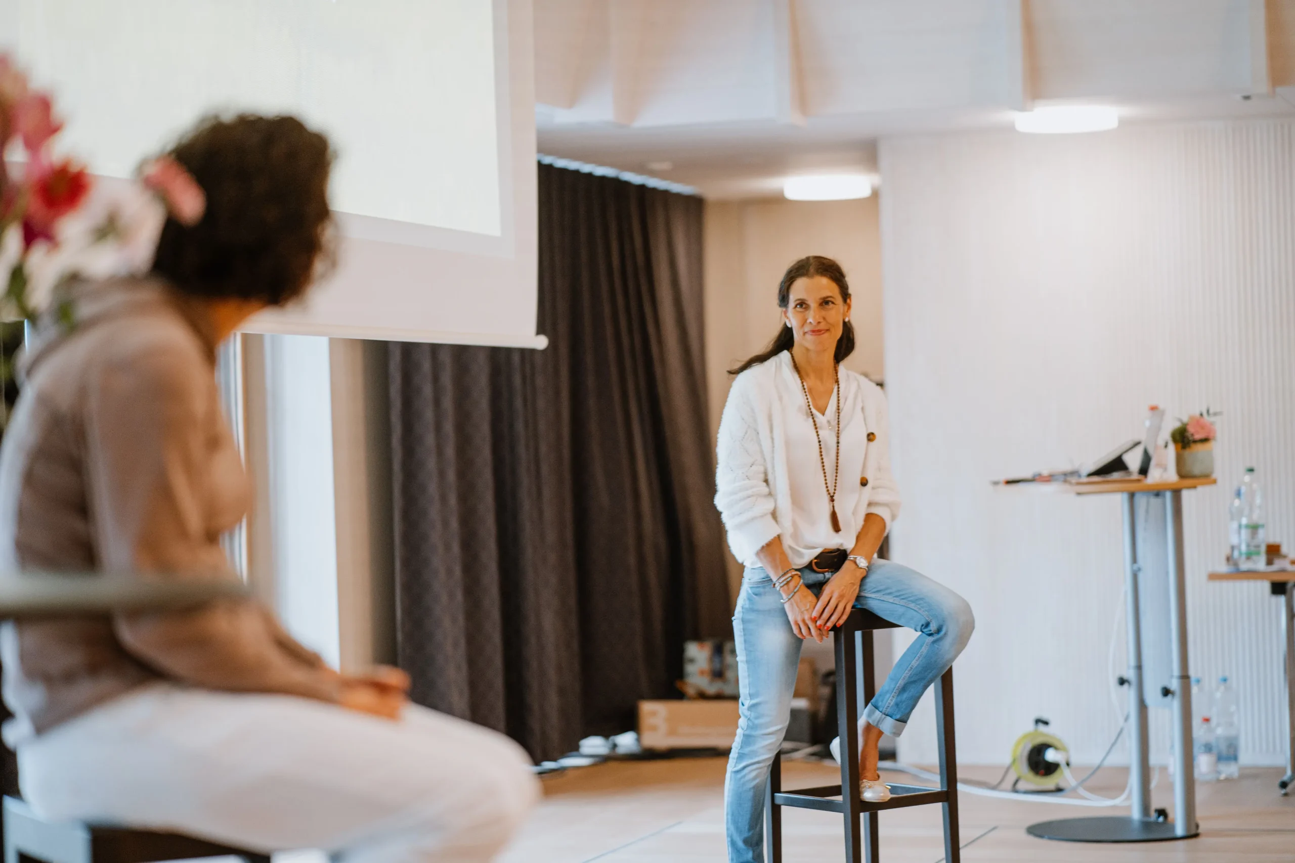 Bulimie Expertin Andrea Ammann sitzt bei einem Ihrer Seminare auf einem Barhocker und redet mit einer Teilnehmerin